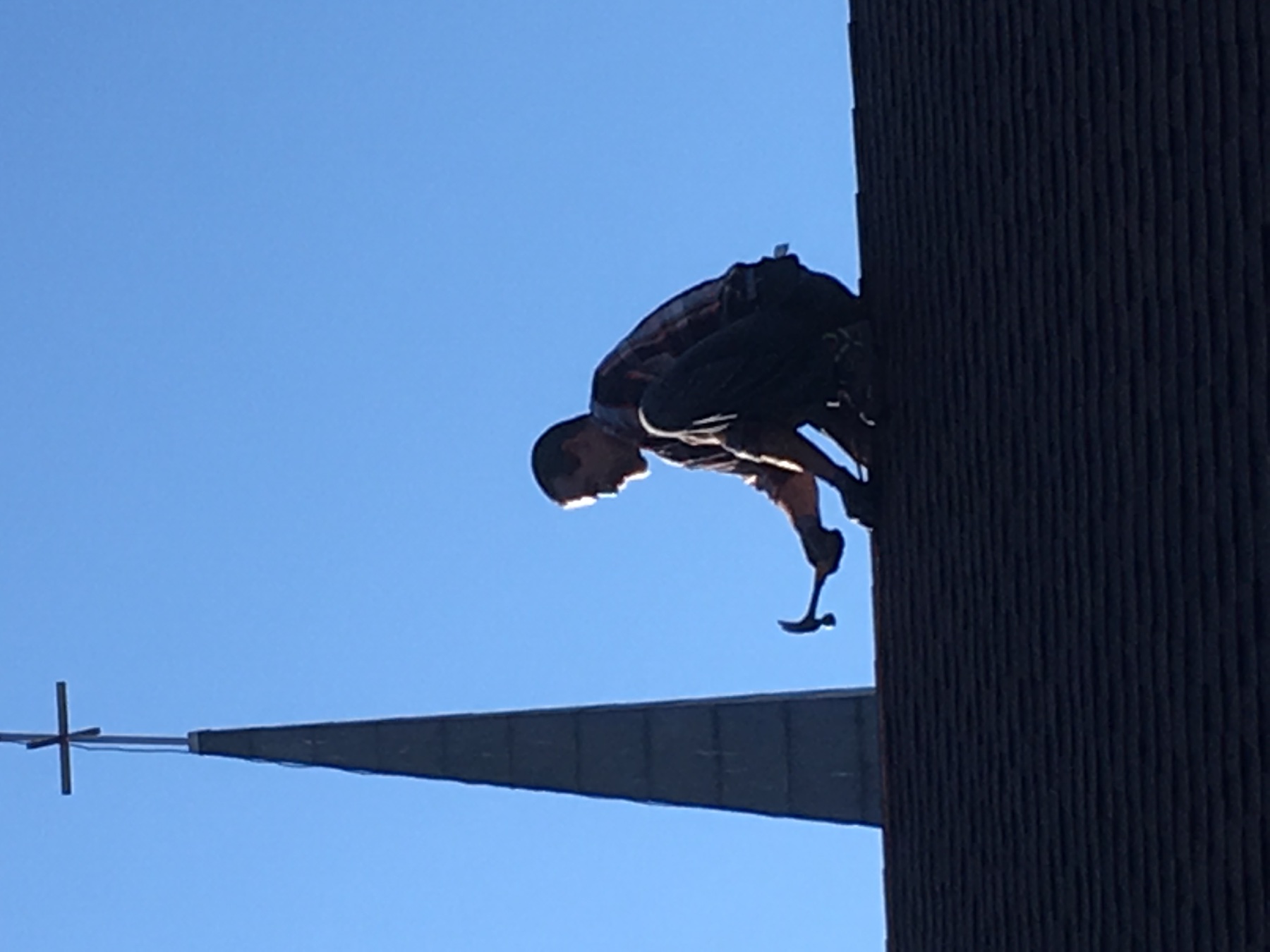 Technician working with a hammer on a rooftop with a church steeple in the background